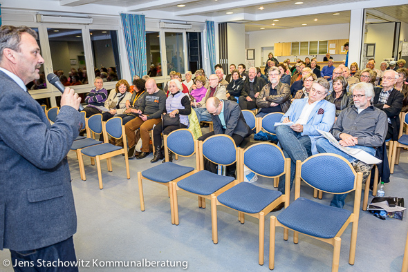 Baudezernent, stehend, spricht zu Menschen im Saal.