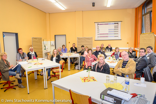 Eine Gruppe von Menschen in einem Klassenzimmer hört der Vortragende zu.