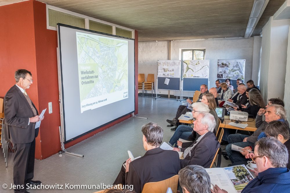 Sprecher steht Gruppe von ca. 20 Personen gegenüber.