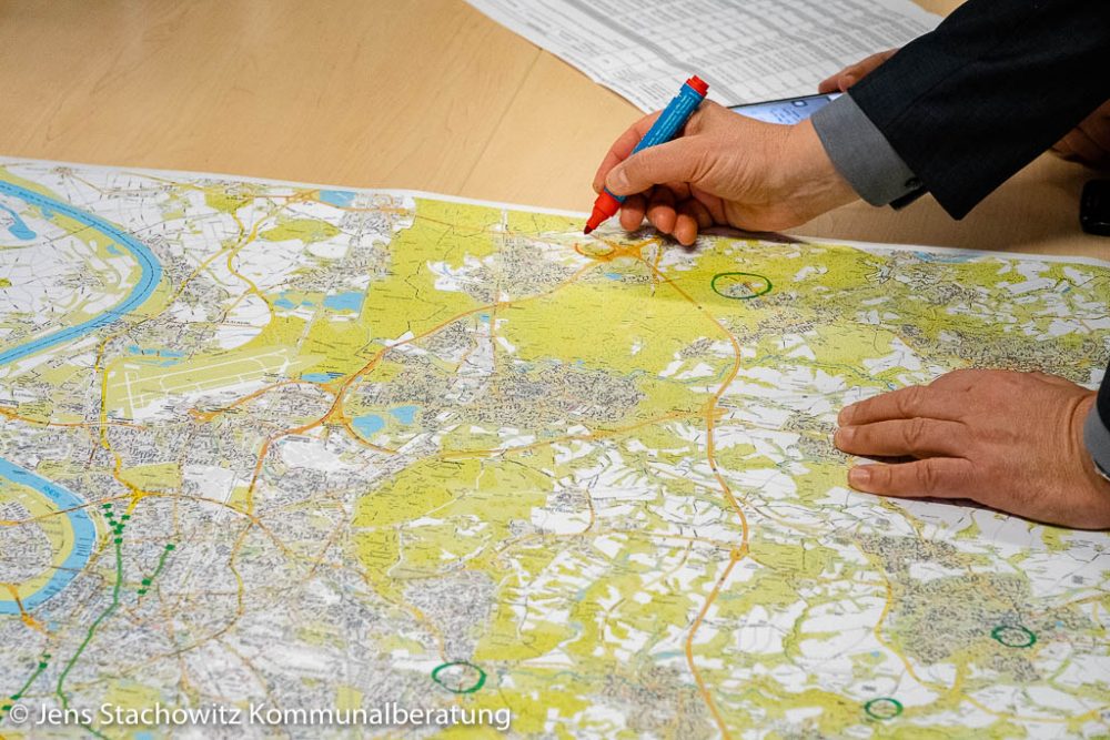 Hand mit Filzstift kennzeichnet einen Standort auf einem Stadtplan
