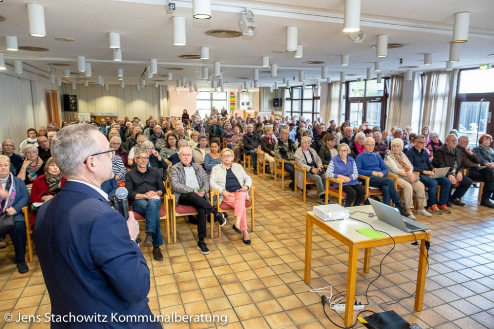 Redner steht vor rund 160 Zuhörenden im Saal.