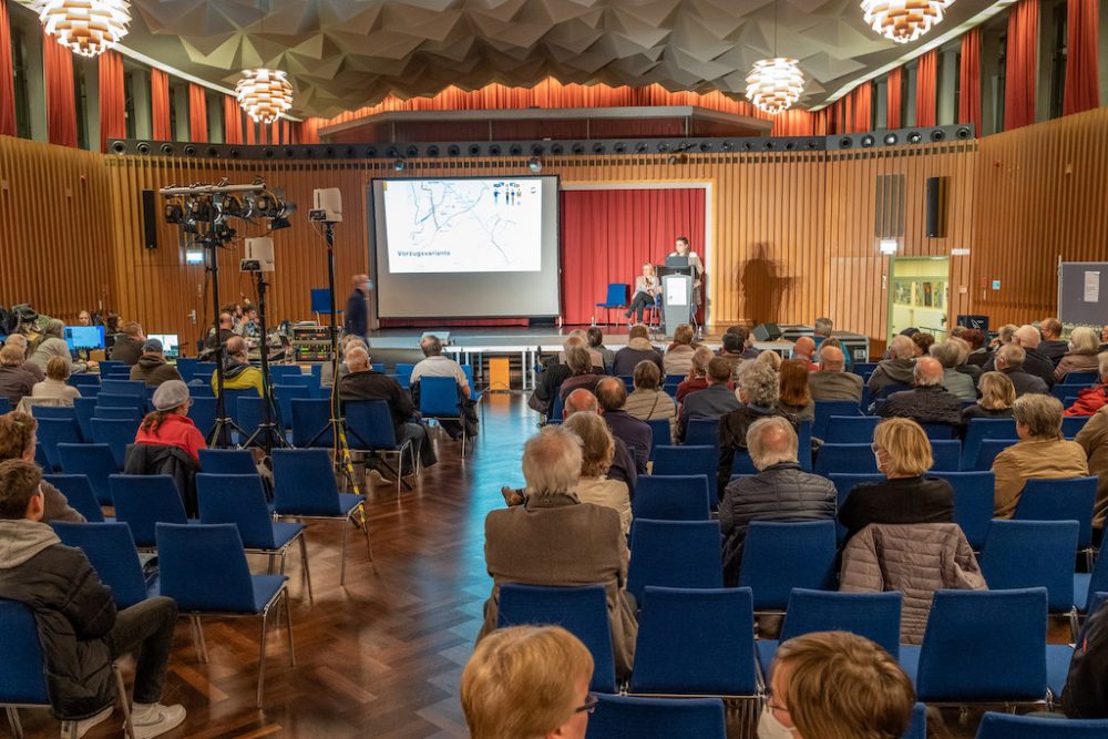 Bürger und Bürgerinnen sind in einer Schulaula versammelt