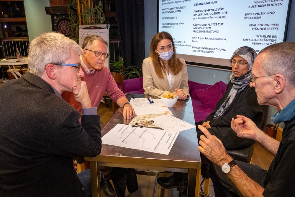 Arbeitsgruppe von fünf Personen sitzt um einen Tisch herum und diskutiert