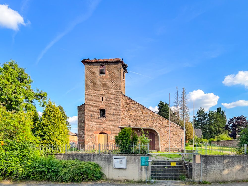 Kirche, deren Kirchturm nach einem Brand fehlt; Grundstück ist eingezäunt