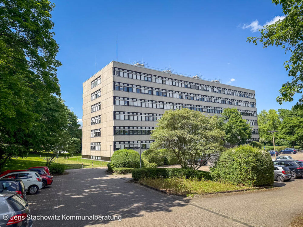 Hochhaus, Parkplatz und Baumkulisse